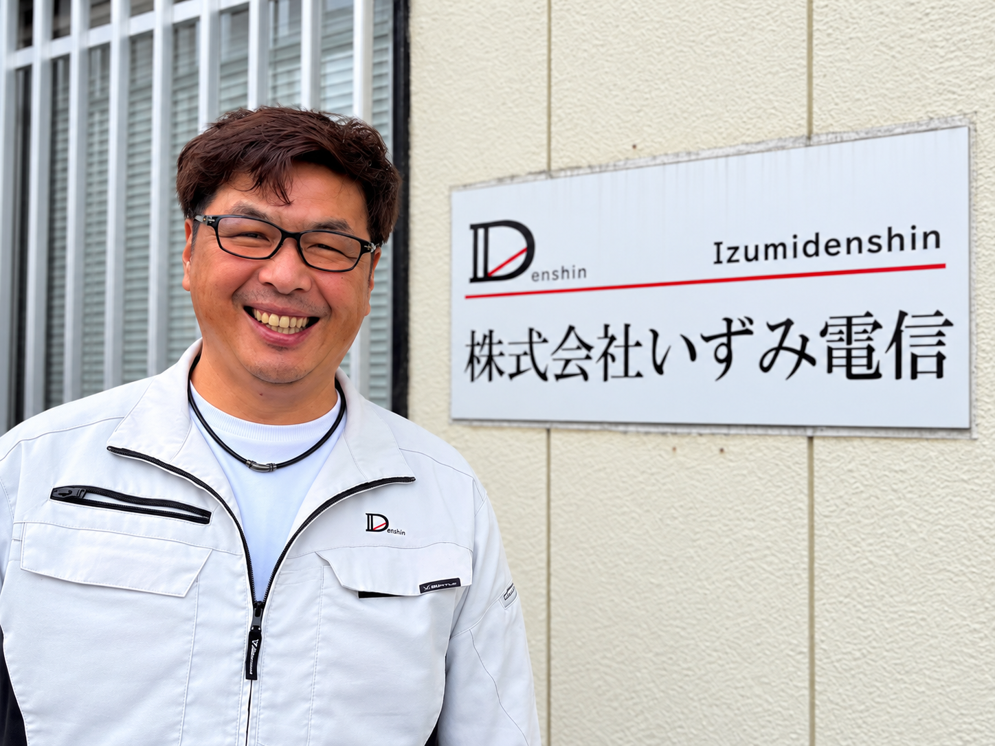 社名看板の前に立つ代表取締役